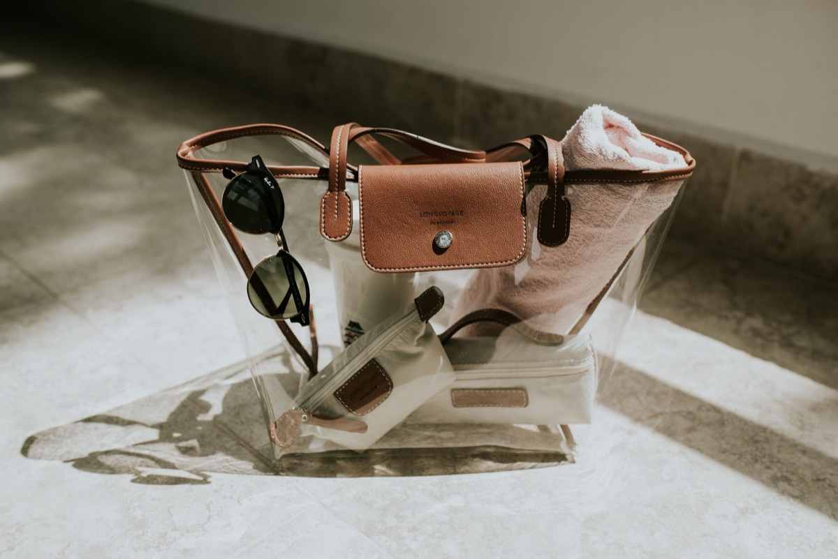A pair of stylish sunglasses placed next to a summer straw hat and beach bag.