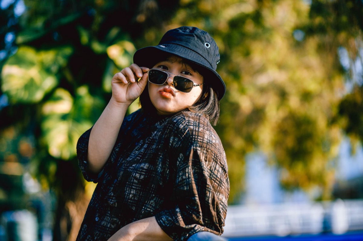 Mulher usando óculos de sol ovais com look de verão.