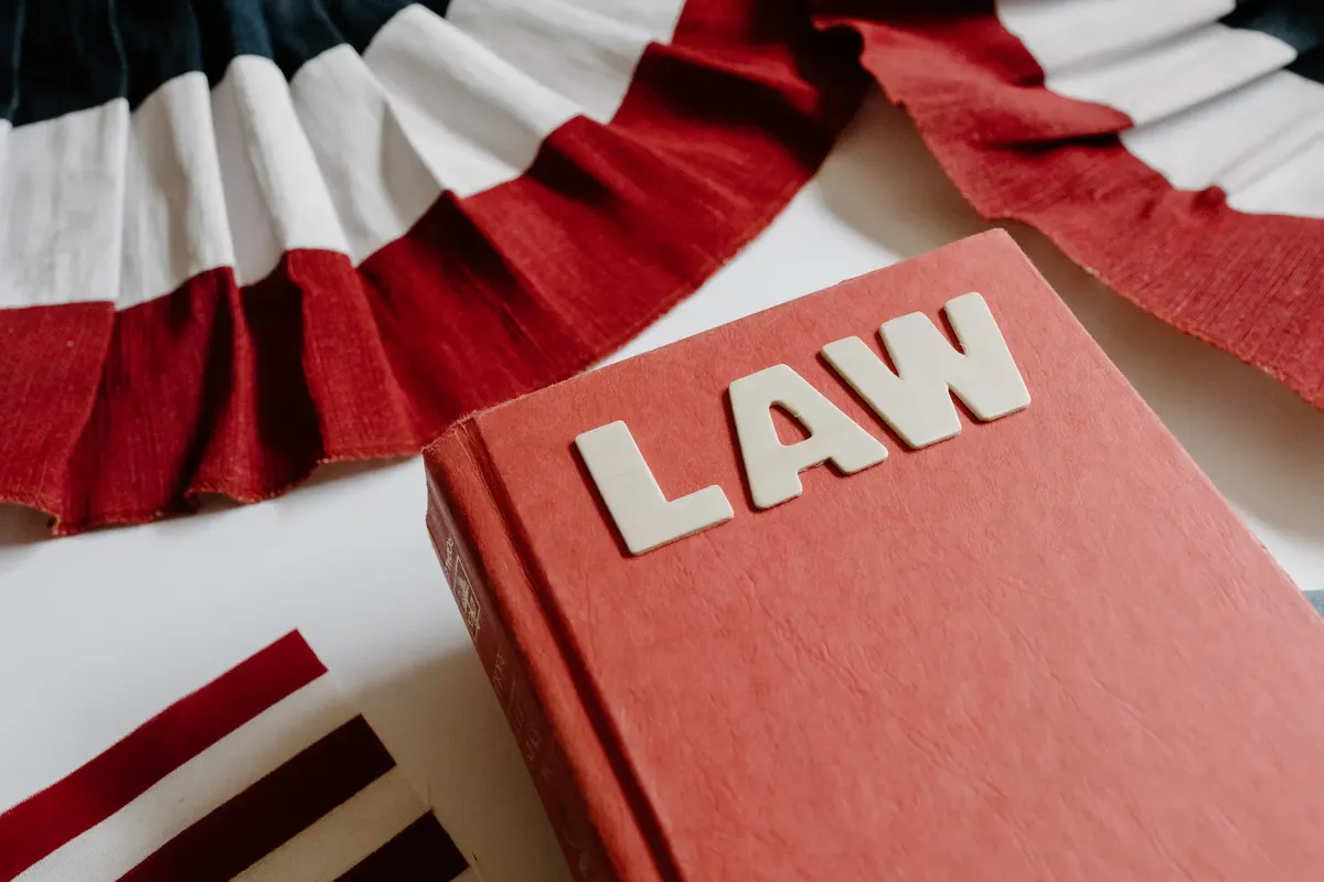 A law book with bold letters placed beside a red, white, and black decorative ribbon.