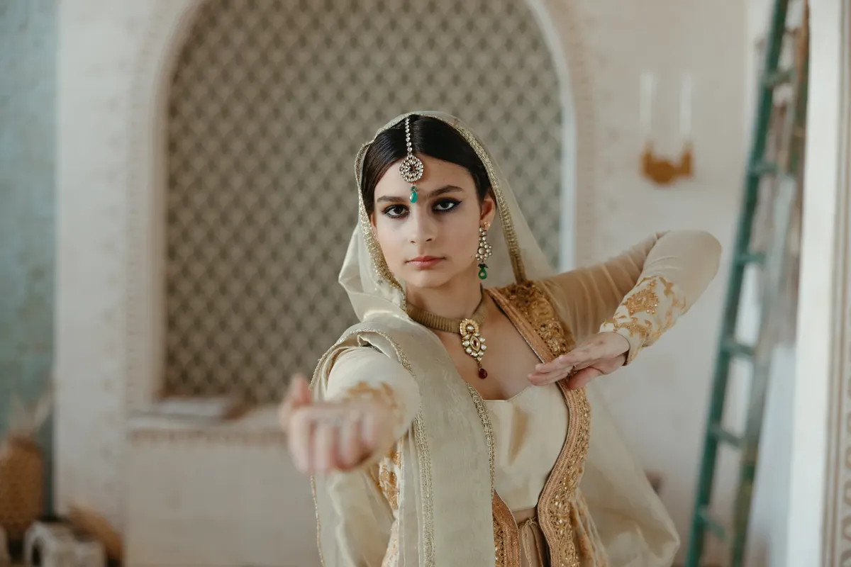 A woman in traditional Indian attire performing a classical dance pose indoors with focused expression.