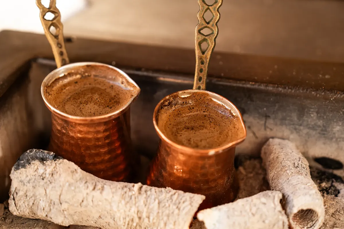 二つの銅の鍋が熱い煤でコーヒーを煮ている。伝統的なトルココーヒー文化を表現しています。