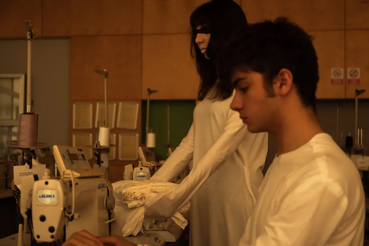 Artistic fashion scene with models in İstanbul sewing workshop, showcasing avant-garde garments.