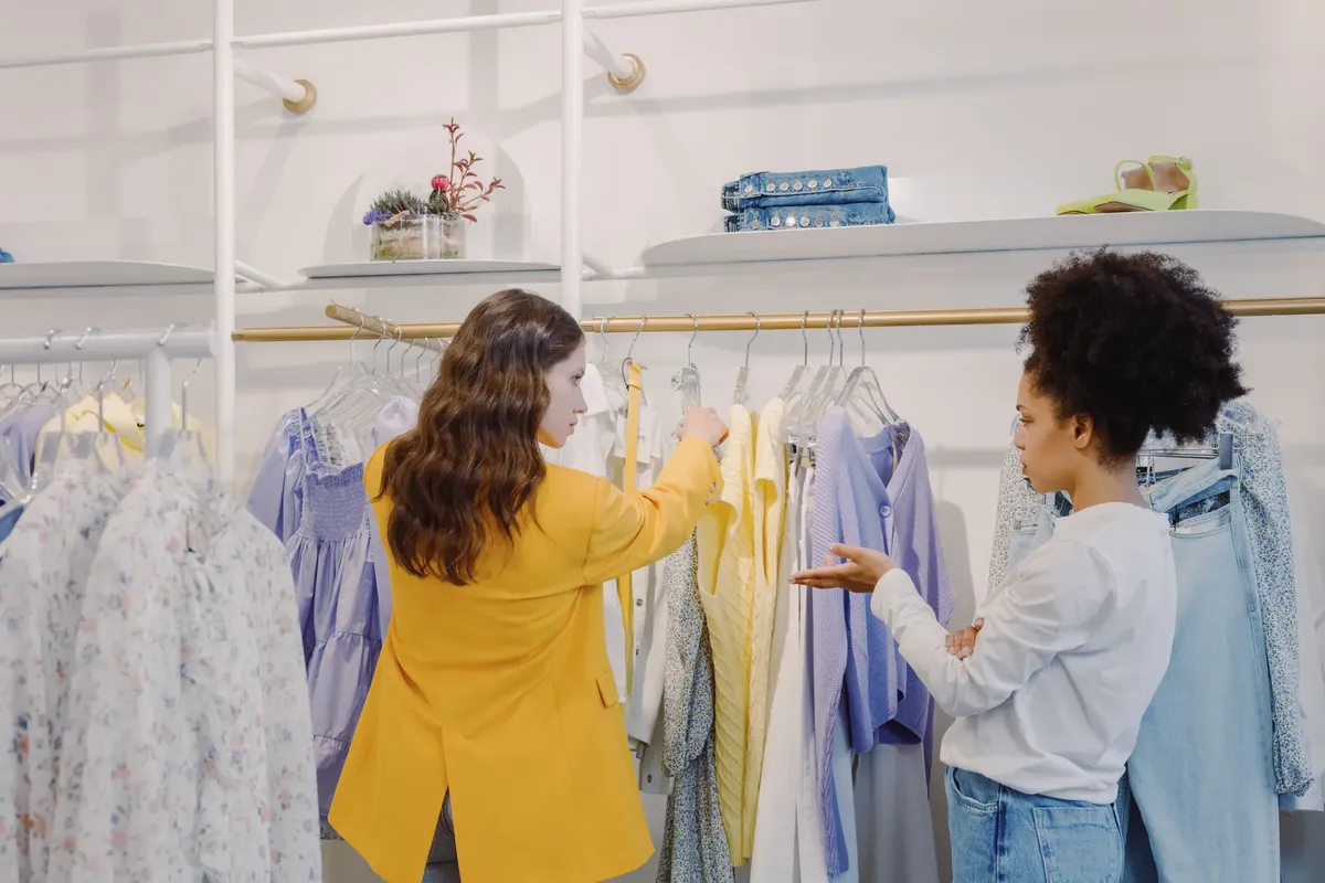 2人の女性がスタイリッシュなブティックでファッションオプションを探索しながら服を購入している。