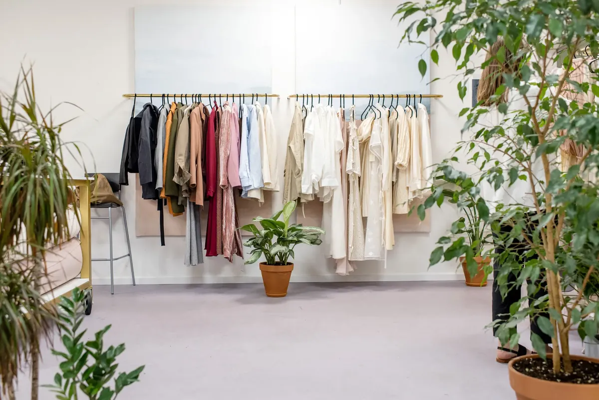 クラシックなファッションショップが、色鮮やかな衣料品コレクションと豊かな室内の植物を展示している。
